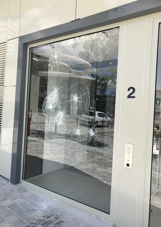 Photo des fissures d'une vitre d'immeuble suite à des impacts